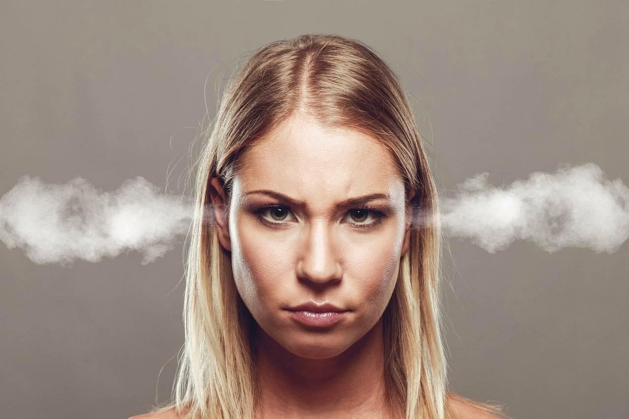 ノートPCに向かいながら、困った表情で髪を押さえる女性