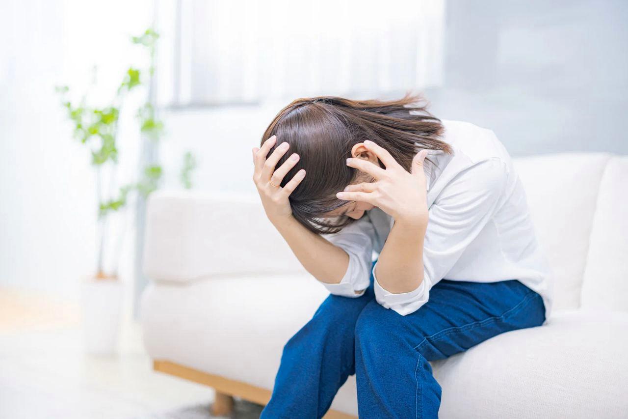 職場で頭を撫でられて嫌な顔をする女性の様子。ストレスが蓄積して疲弊している様子。